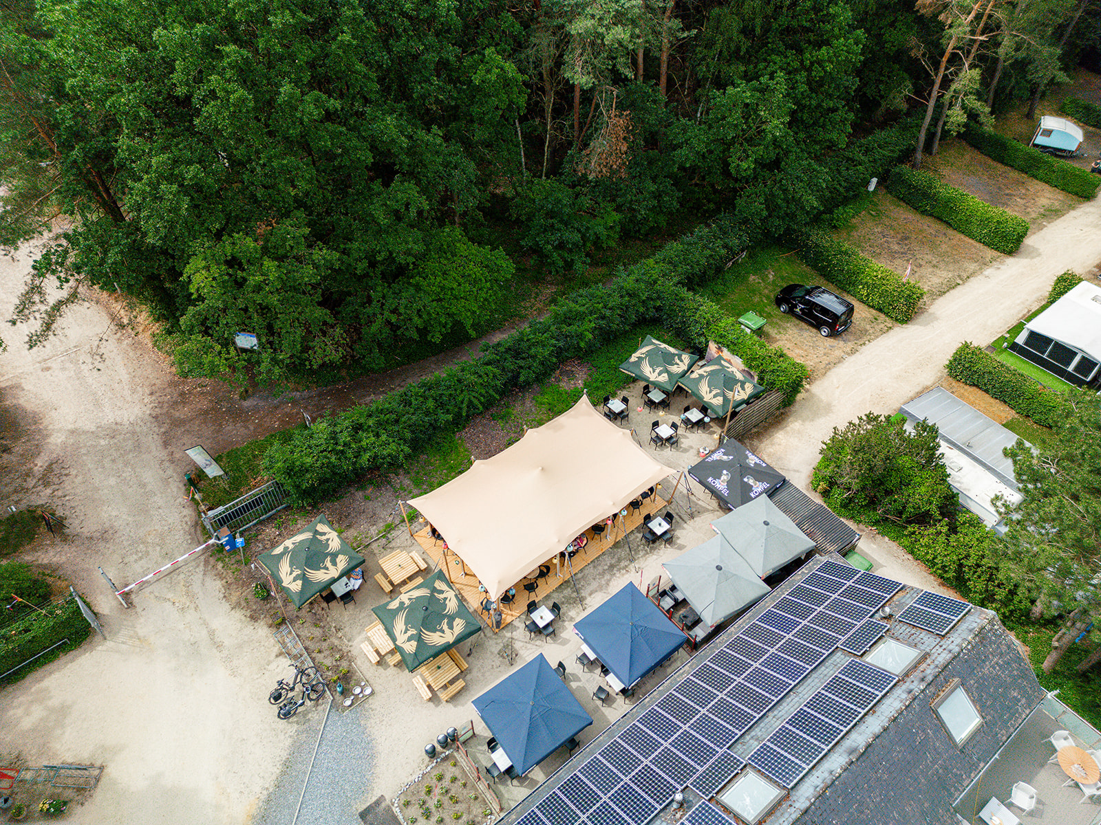 Espace du bar de camping aménagé sous la toile et les mâts bois